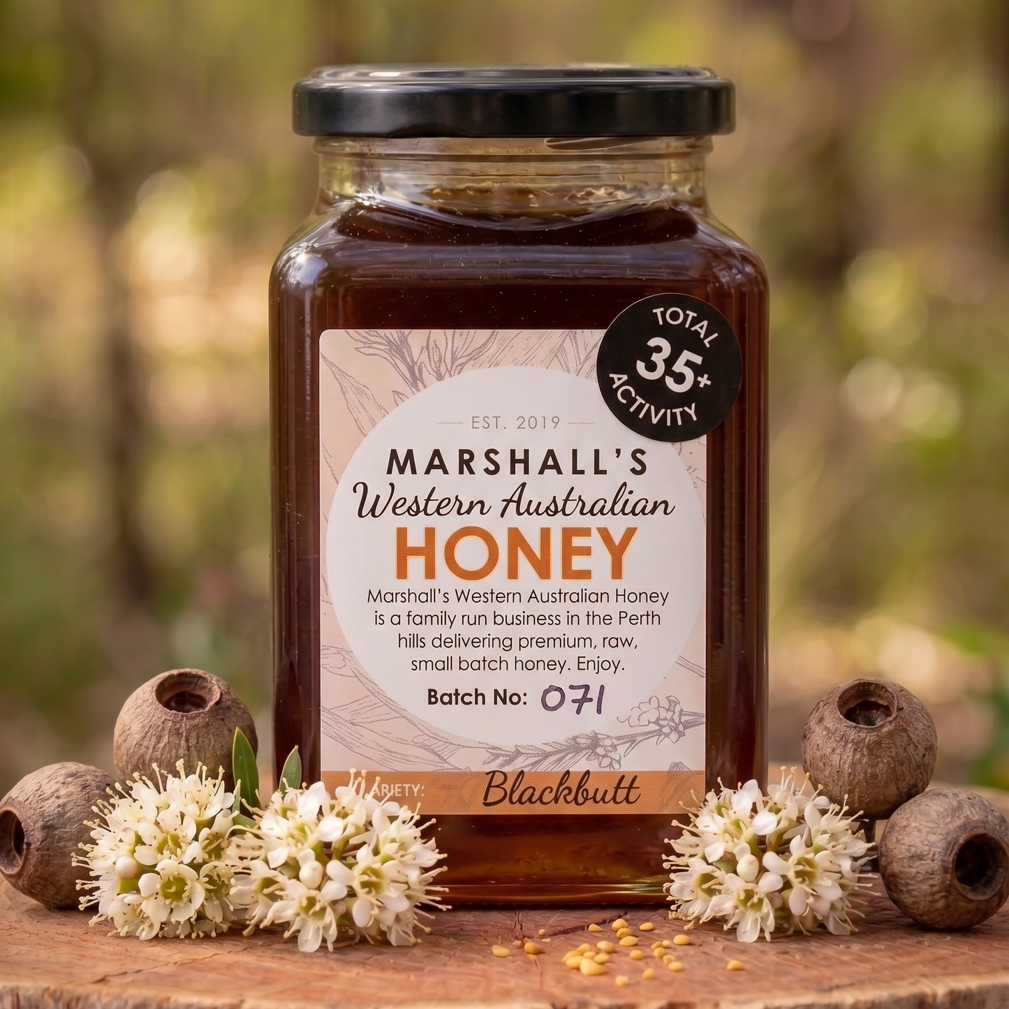 Jar of Marshall's Western Australian Honey on a wooden surface with flowers and honeycomb pieces.